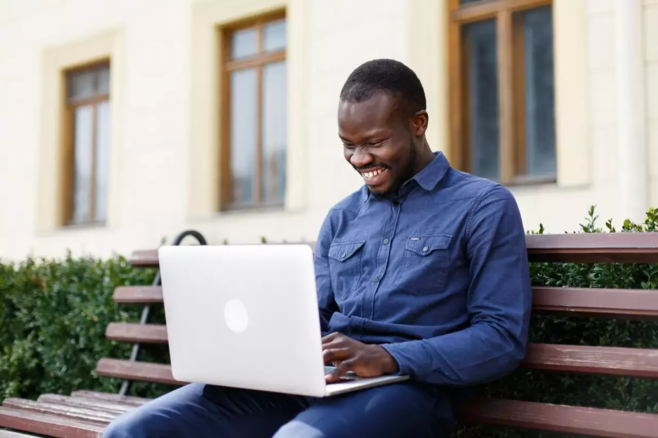 happy african american man works his laptop sitting bench outside 8353 5290